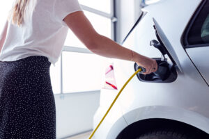 woman plugging in electric car in garage at home